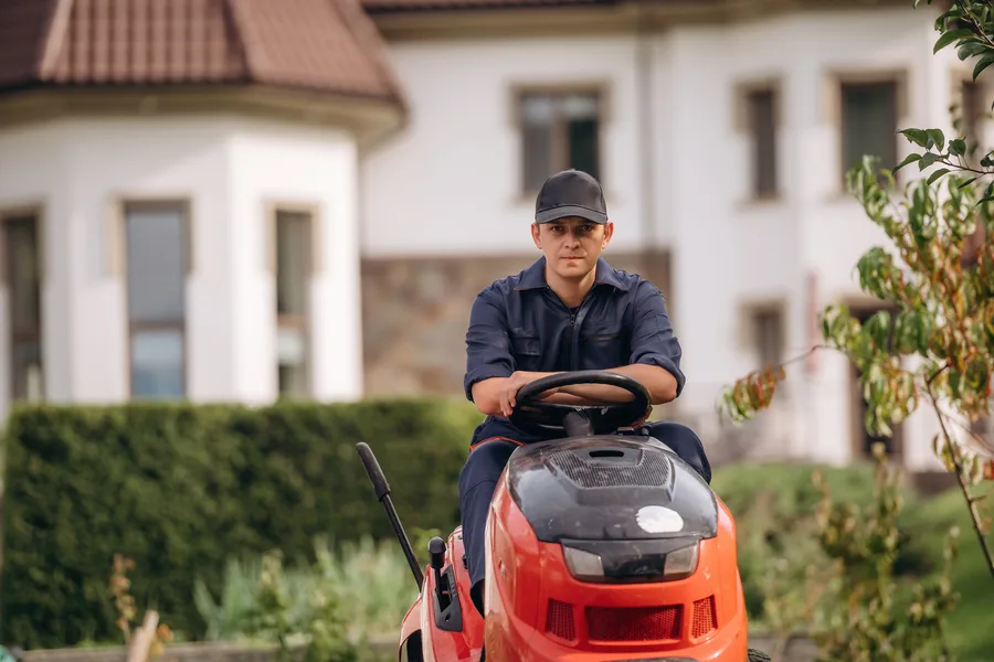 Jardinier professionnel sur une tondeuse autoportée dans un grand jardin